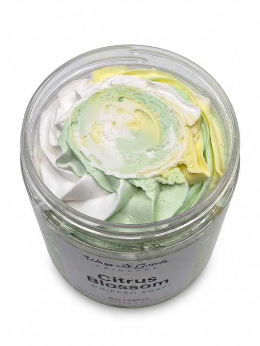 Jar of whipped soap with green, white, and yellow swirls on a white background